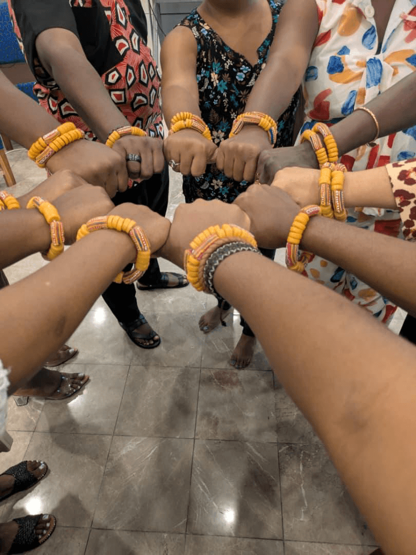 Mains de participantes réunies avec des bracelets lors d'une activité collective.
