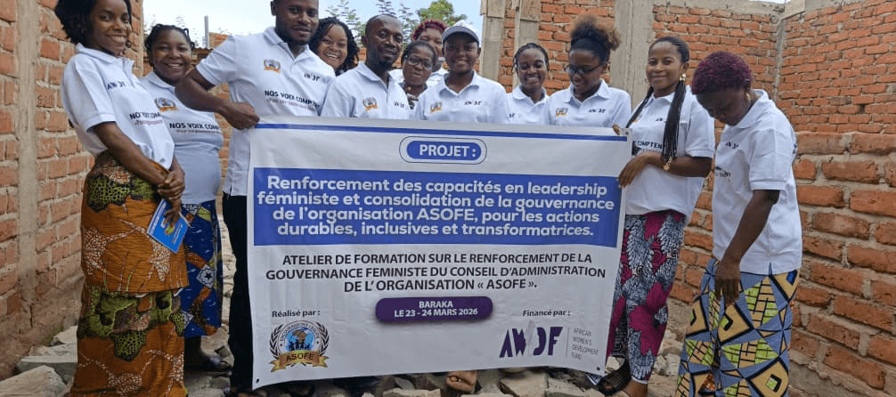 Groupe de participantes en RDC tenant une banderole de formation en leadership féministe et gouvernance.