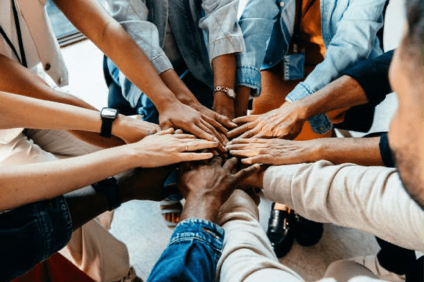 Une équipe diverse réunit ses mains pour symboliser la coopération et le leadership collectif